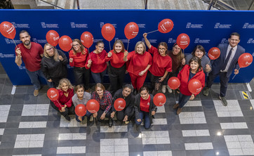 Pracownicy Politechniki Rzeszowskiej w czerwonych strojach, z czerwonymi balonami,